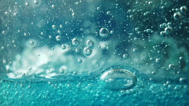 Bubbles fall in slow motion in blue fluid, liquid dish soap macro