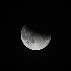 Naklejka premium close up view of a partial lunar eclipse in the black night sky