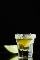 Tequila shot with lime and sea salt on black background