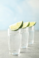 Tequila shots with lime slices on grey background