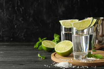 Tequila shots with lime slices, salt and mint on wooden background