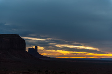 Early morning light of dawn, contasted against the black mesa walls of monument valley.