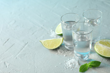 Fototapeta na wymiar Tequila shots, salt, lime slices and mint on white cement background