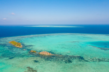 Atoll and blue sea, view from above. Seascape by day. Turquoise and blue sea water. Small islands on the reefs.