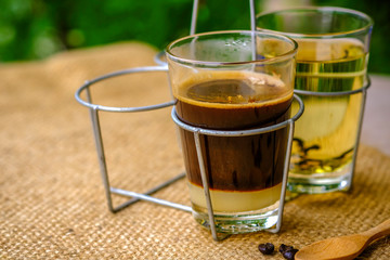 a glass of black coffee with condensed milk in retro style coffee shop
