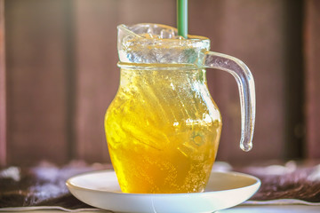 a mug of lemon ice tea  serving on wooden table with brown background