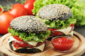 Two black burgers with vegetables and beef meat	