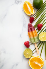 Summer ice lollies with fruit and a tropical palm leaf