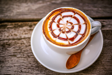 A cup of hot coffee with latte art on wooden table in day light