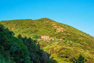 Fototapeta na wymiar Houses on the high green hill at Adriatic sea coastline in Montenegro
