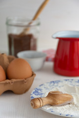 Top view of ingredients for pastry, brown sugar, flour and eggs on white wooden background