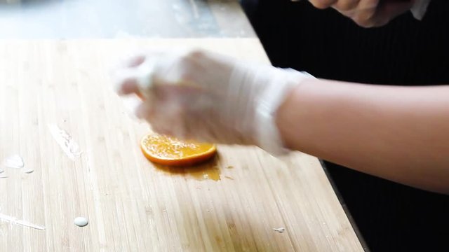 The cook puts a slice of orange on cheesecakes with sweet sauce