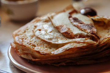 Stack of hot classic Russian thin pancakes. Rustic style. Traditional for the Russian pancake week - Maslenitsa. Close-up. Wooden spoon on the pancakes.