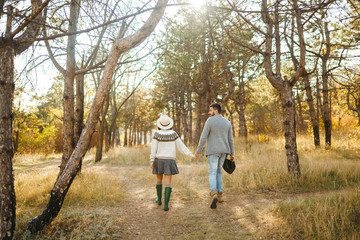 Lovely hipster couple enjoying each other. Couple wearing beautiful hats and sweaters. Lifestyle, happy couple of two play on a sunny day in the park. The concept of youth, love and lifestyle. 