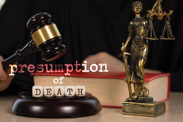 Words PRESUMPTION of DEATH  composed of wooden dices. Wooden gavel and statue of Themis in the background.
