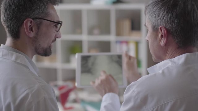 Two Skill Experienced Male Doctors Checking X-ray Of The Lungs On The Tablet, Discussing. Concept Of Medicine, Health Care And People, Hospital. New Modern Fully Functional Medical Facility.