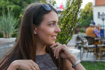 Outdoor portrait of a young smiling woman sitting on the park bench