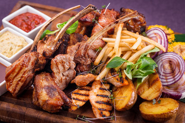 rack of lamb, chicken skewers, pork skewers on a wooden board