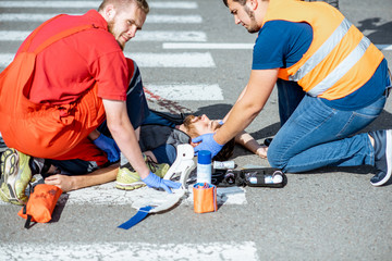 Dispair ambluence worker applying emergency care to the injured bleeding man lying on the...