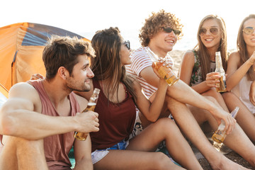 Group of cheerful happy friends camping at the beach
