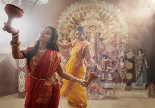 Two Married bengali women performing dhunuchi dance on the occasion of durga puja