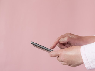Woman hands using her mobile phone on pink background with copy