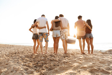 Back view of a group of people standing at the beach