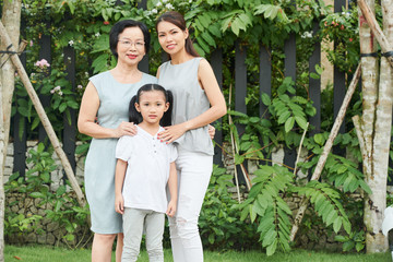 Naklejka na ściany i meble Portrait of Asian family generation standing outdoors and smiling with green trees in the background