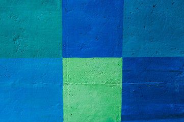 Concrete wall painted in squares of blue and green.