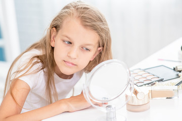 Young girl admires her reflection in the mirror
