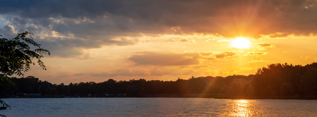 Fototapeta na wymiar Panorama of orange romantic sunset over lake on a beautiful summer evening. 