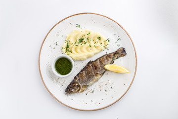 Grilled whole fish with mashed potato, lemon and soy sauce isolated on white background