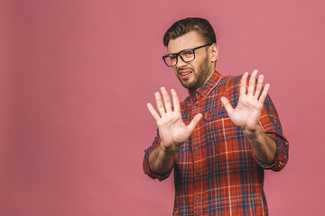 Photo of young man pushing hand forward as if refusing something, wanting to stop sign, isolated on...