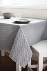 black plates on the table with a gray tablecloth, table setting with beautiful dishes, a table by the window