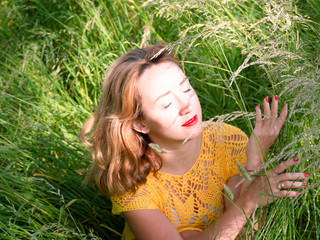 Gorgeous happy mature woman sitting, standing, laying on the grass relaxing at the local park adjusting her hat smiling looking away dreamily