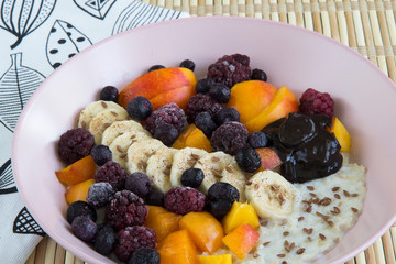 Oatmeal with bananas, apricots, blueberries, blackberries, chocolate paste and sesame seeds