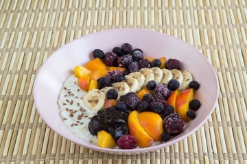 Oatmeal with bananas, apricots, blueberries, blackberries, chocolate paste and sesame seeds