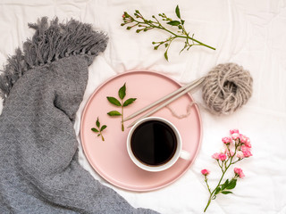 Frühstück im Bett, Kaffee, Blumen und ein Wollknäuel auf einer weißen Bettdecke, Hygge, Flat lay