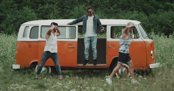 Three young guys dacing in front of a retro bus in the middle of nature very charismatic