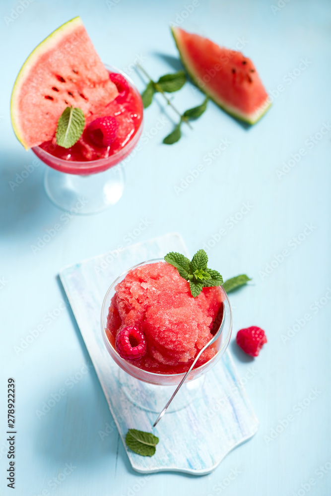 Wall mural Watermelon slushy, summer refreshing drink on blue background, frozen with raspberres