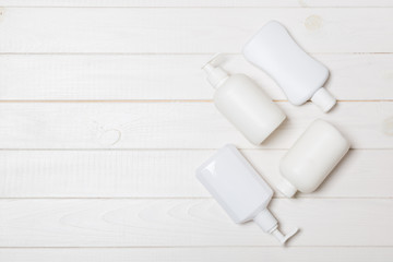 Set of White Cosmetic containers on wooden background, top view with copy space. Group of plastic bodycare bottle containers with empty space for you design