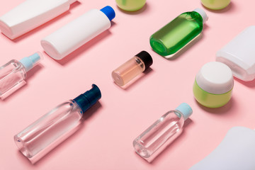 Top view of cosmetic containers, sprays, jars and bottles on pink background. Close-up view with empty space for your design