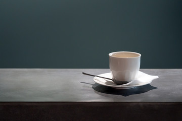 A cup of coffee on the bar counter on a dark, cold background