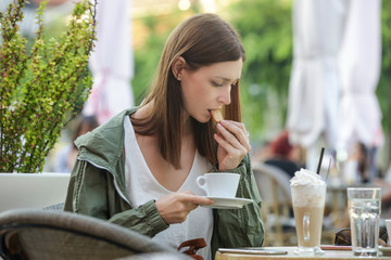 Portrait of a young beautiful woman sitting in a cafe outdoor drinking coffee 