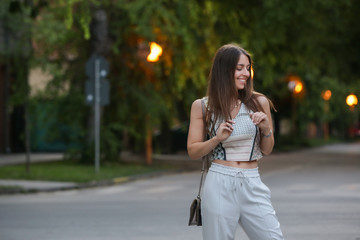 Young fashionable woman posing on the street in the summer evening