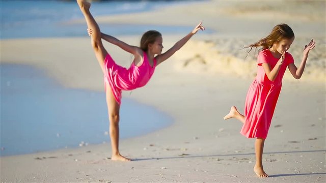 Two little happy girls have a lot of fun at tropical beach playing together