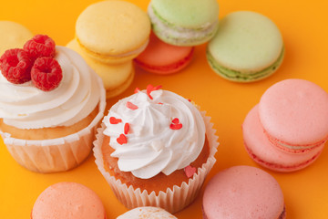 Delicious cupcakes with icing on a yellow background