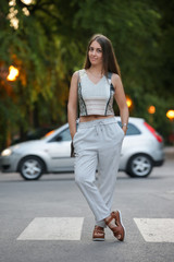 Young fashionable woman posing on the street in the summer evening