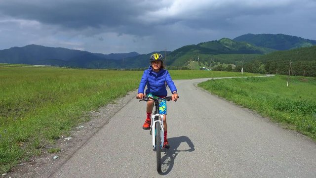 Teenage boy riding bycicle on mountain road in cloudy day
