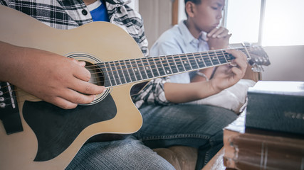 Fototapeta premium Young christian playing guitar and praying God on wooden table. christian concept.